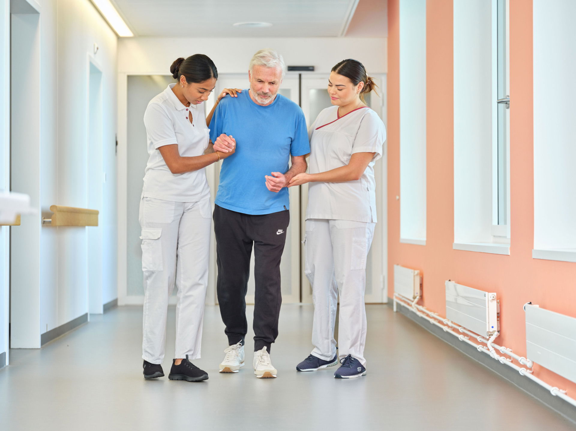 Pflegende helfen einen Patient am Laufen